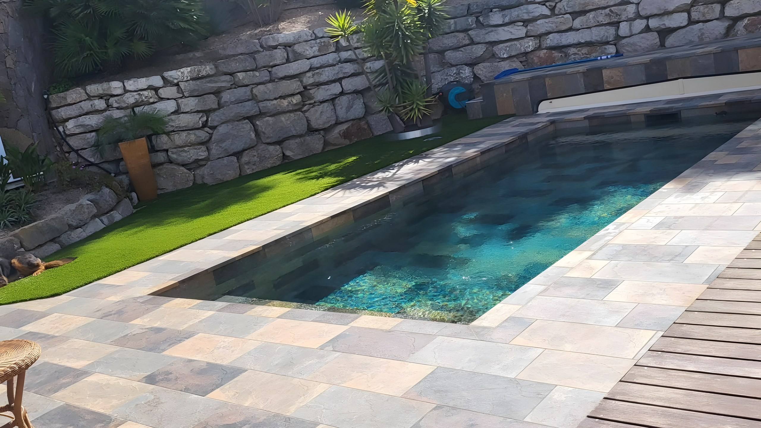Terrasse et margelles en quartzite posées autour d'un bassin, devant un mur en pierre sèche